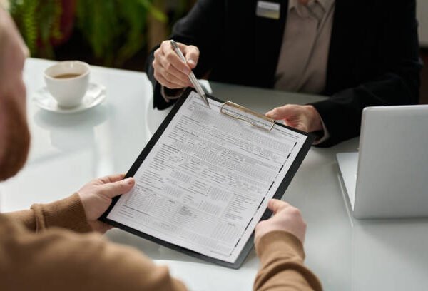 Closeup of insurance advisor handing application form to client during consultation